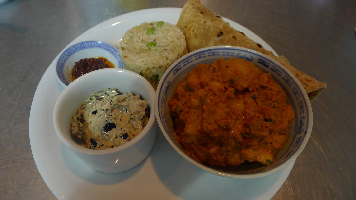 Our Thali, clockwise from top left: chilli jam; caramelised onion and peas pulao; chapatti; channa masala; aubergine raita